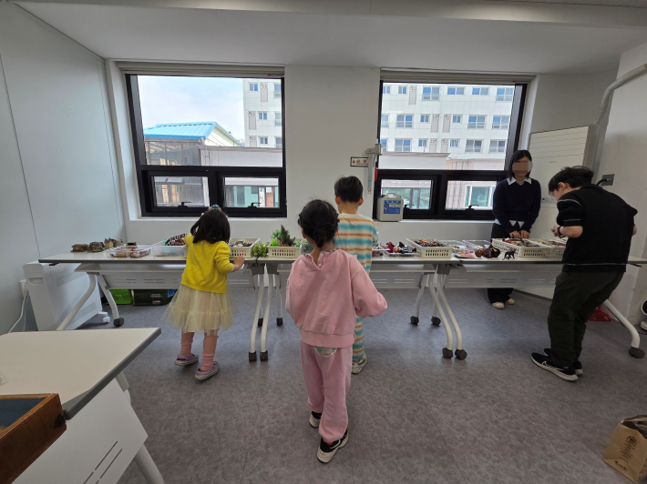 자신의 이야기를 표현하기 위해 모래상자에 놓을 피규어를 고르는 아이들 모습