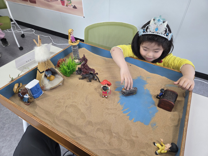 아이가 모래상자를 꾸미며 집중하는 모습