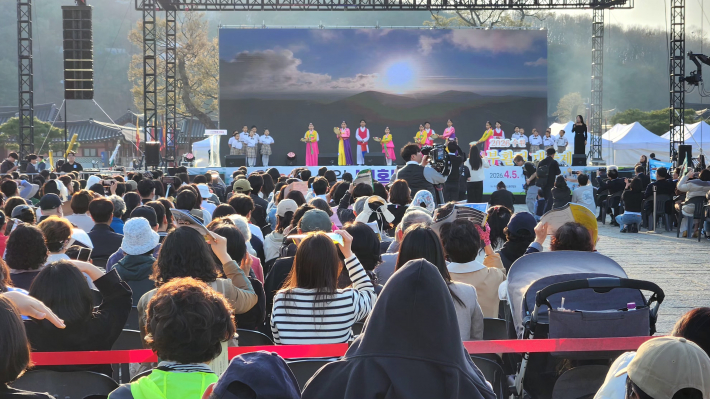 화려한 무대 조명 아래 합창단의 역동적인 퍼포먼스가 펼쳐지고 있다.