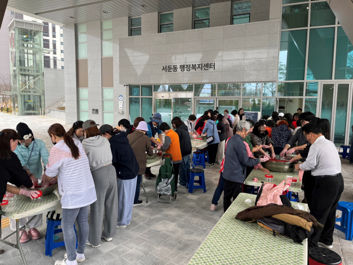 주민들이 직접 딸기를 으깨며 딸기청 만들기 체험을 즐기고 있는 모습