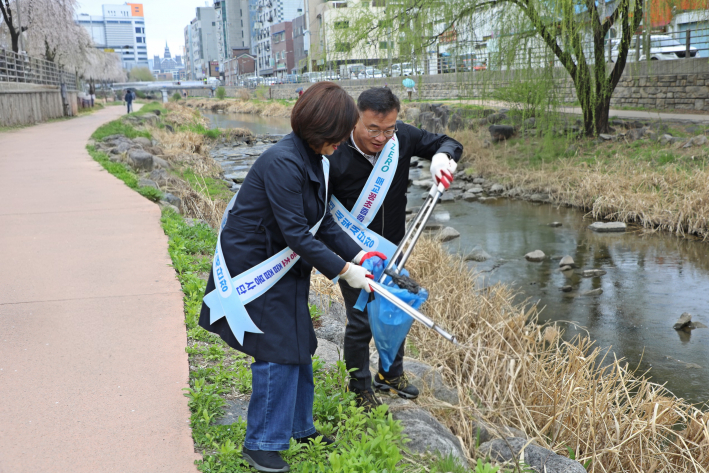 수원천에서 팔달구청과 매교동장이 쓰레기를 주우며 환경정화 활동을 하고 있다.