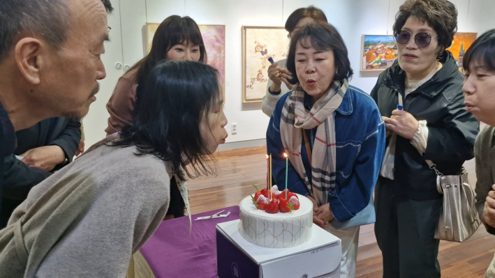 오픈식에서 촛불을 꺼고 있는 회원들의 표정은 밝다.