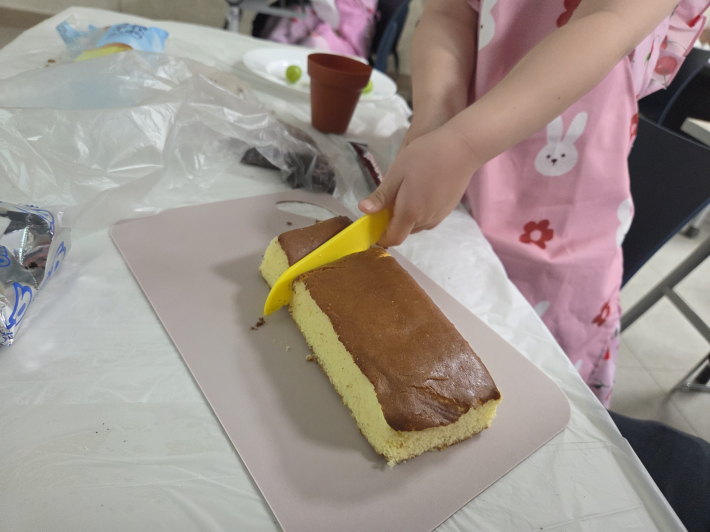 카스테라를 직접 플라스틱 칼을 이용해 자르는 아이