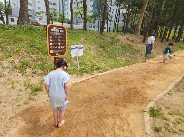 신발을 벗고 황톳길을 맨발로 걸으며 자연을 느끼는 시민의 모습