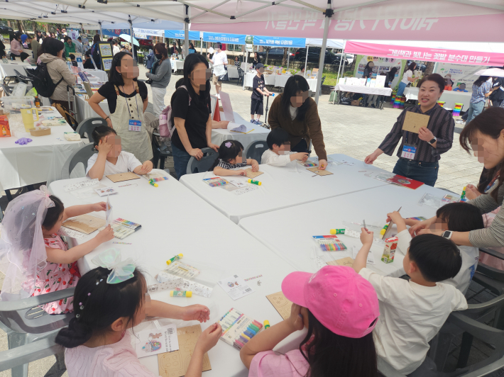 호매실도서관 동아리 '이야기밥' 체험부스에서 아이들과 함께 쉐이커 키링 만들기 체험활동이 진행되는 모습 