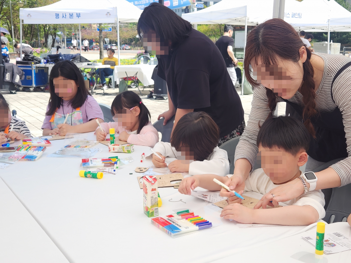 반짝이는 재료를 활용해 나만의 키링을 만드는 어린이 참가자들