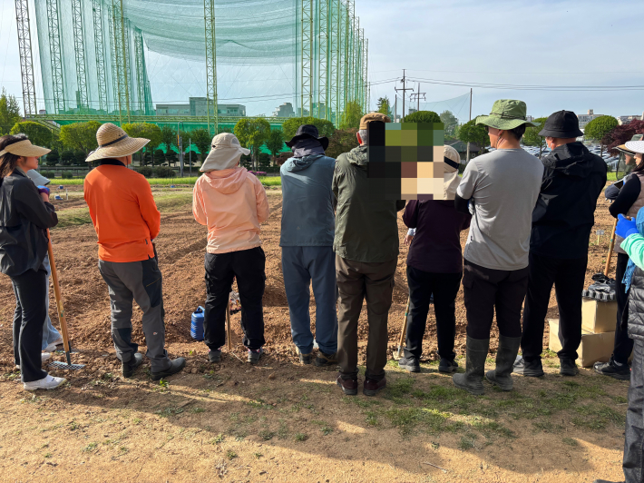 텃밭에서 비료 강의 듣는 수강생