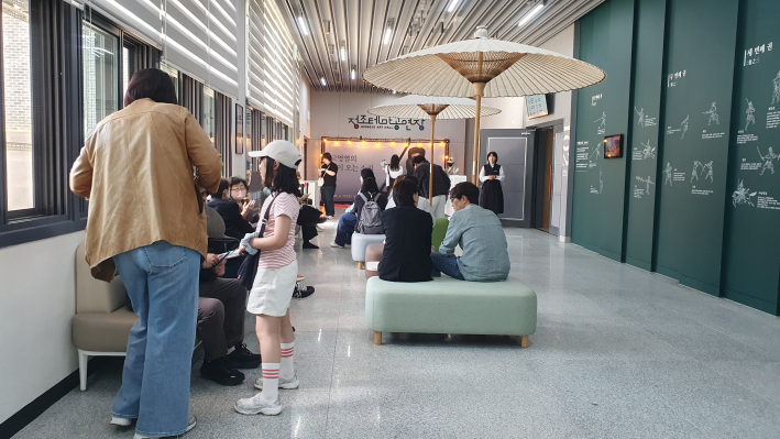 공연 시작 전 정조테마공연장 로비. 한국 전통 우산 조형물이 놓인 공간에서 관람객들이 삼삼오오 모여 공연을 기다리고 있다.