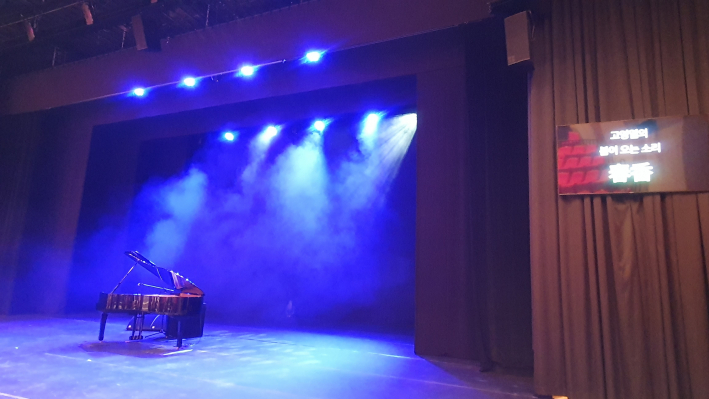 푸른 조명과 안개 연출 속 무대 위 그랜드 피아노. 오른쪽 전광판에는 '고영일의 봄이 오는 소리'가 표시돼 있다.