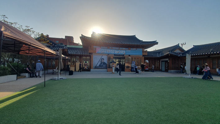 저녁 노을빛이 물드는 공연장 외관. 고영일 공연 포스터가 붙은 정조테마공연장 입구로 관람객들이 발걸음을 옮기고 있다.