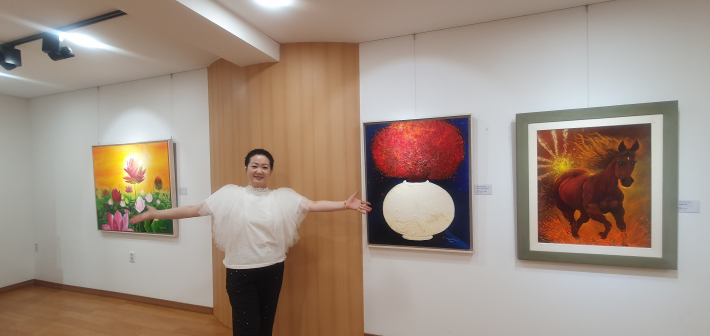 윤혜숙 작가의 연꽃과 말 작품이 전시된 공간. 생동감 있는 색채와 역동적인 구성이 인상적이다.