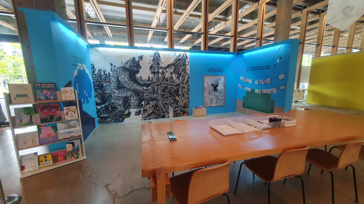 전시장 한쪽에 마련된 체험 공간과 그림책 서가. 관람객은 작품 감상 뒤 그림책과 활동지를 통해 전시를 이어 경험할 수 있다.