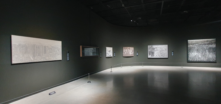 검은 벽과 낮은 조명으로 구성된 전시장 전경. 기사 초입의 '한낮의 빛에서 검은 전시장으로 들어가는 느낌'을 시각적으로 보여준다.