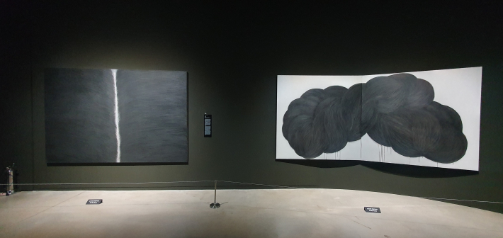 최수환의 '빔_바다'와 유혜숙의 '무제'가 나란히 놓인 장면. 빛과 검은 덩어리, 흰 화면이 대비되는 장면이라 작품 설명 구간에 어울린다.