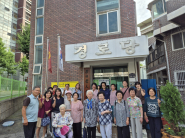 수리한 경로당 현판을 걸고 경로당 어르신들과. 마을만들기 협의회 회원들이 사진을 찍고 있다.