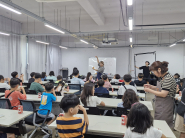 강사가 가죽 지갑 만들기를 아이들 눈높이에 맞게 그림을 곁들여서 설명하고 있다. 
