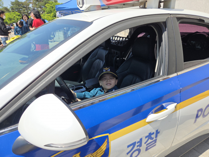 경찰복을 입고 경찰차 운전석에 앉은 어린이