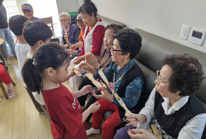 아동이 드리는 효자손을 받고 기뻐하는 어르신 모습