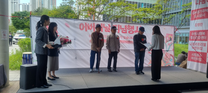 3명의 장수상 수상자가 관장으로부터 상장과 부상을받고 있다. 
