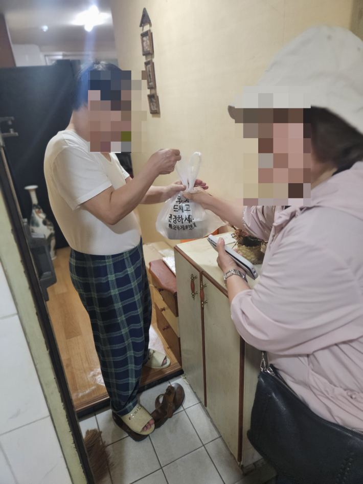 협의체위원님이 대상자에게 반찬을 전달하는 모습입니다.
