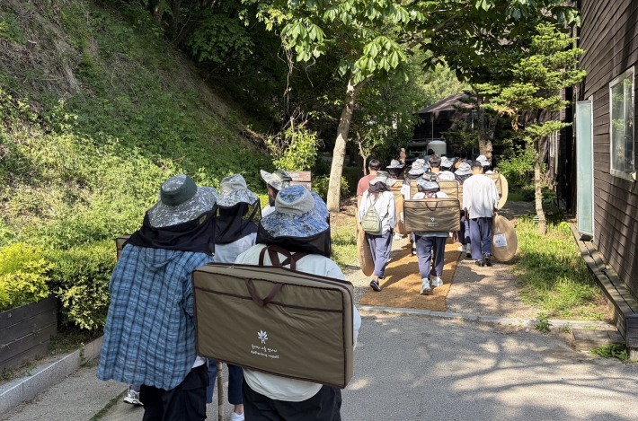 자연속에서 스트레스를 완화할 수 있는 숲 테라피 프로그램에 참여하기 위해 담소를 나누며 걸어가는 모습
