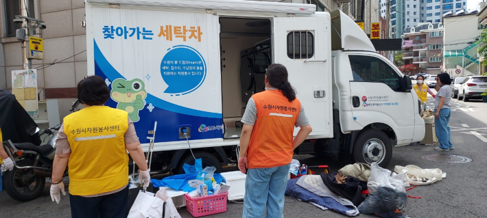 자원봉사센터 봉사자들이 대상자 가정에서 세탁물을 수거해서 찾아가는 세탁차에 옮기고 있다.