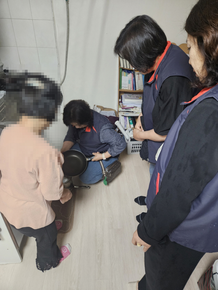 노후된 프라이팬을 새로운 프라이팬으로 바꾸고 안부를 확인하고 있는 지역사회보장협의체 위원