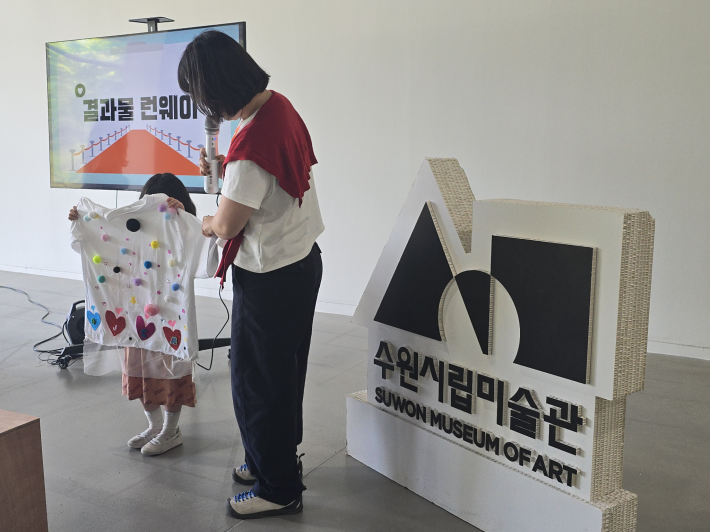 완성된 옷을 입은 어린이가 발표 시간에 자신의 작품을 선보이고 있다.