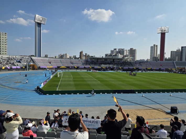 수원FC 홈경기를 찾은 시민 응원단이 관중석에 앉아 양손에 응원 도구를 든 채 선수들에게 힘찬 함성과 박수를 보내고 있다.