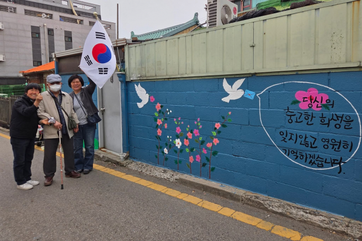 국가유공자의 집 벽화 앞 기념사진(좌로부터 김미신 단장, 정수필 국가유공자, 율천동 동장)