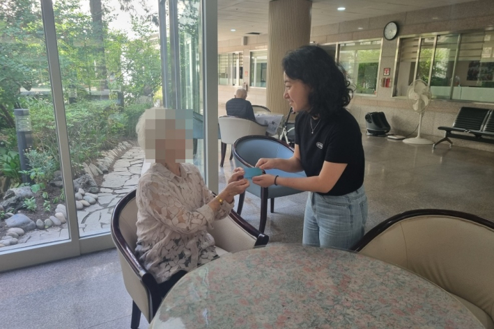 직원이 어르신에게 고유가 피해지원금 카드를 전달하고 있다