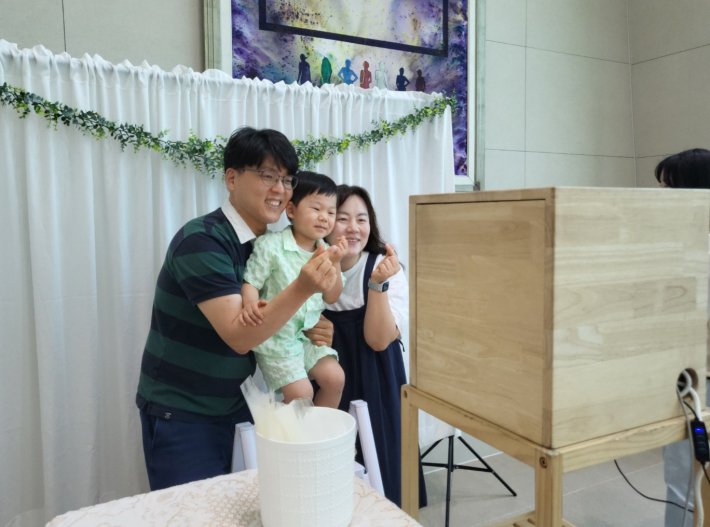 이벤트로 마련된 즉석 사진 촬영에 참여한 아이와 부모가 함께 행복한 미소를 짓고 있다.
