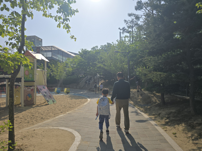 고등동 30통 박종욱 통장이 아이의 손을 잡고 등교를 돕고 있다. 수원새빛돌봄 등하교 동행돌봄 서비스는 지역을 잘 아는 주민이 아이의 이동을 지원한다.