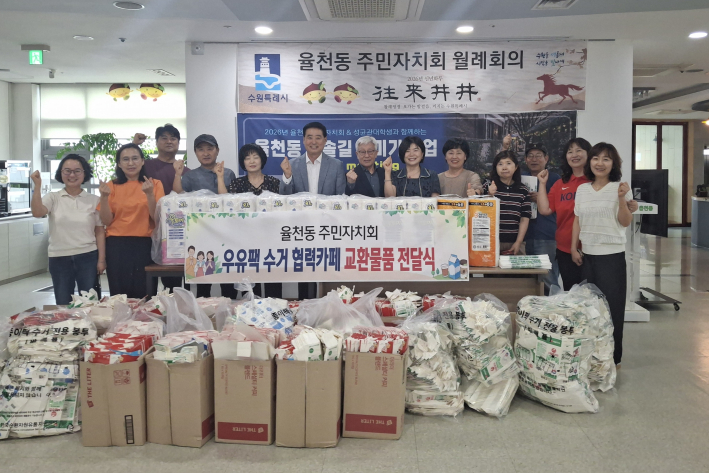 율천동 주민자치회 위원들이 우유팩과 교환물품 앞에서 기념사진을 찍고 있다.