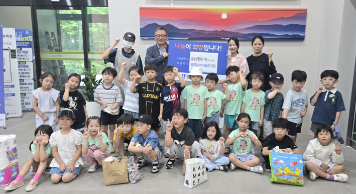 꿈꾸는 아이들 유치원 원아들과 선생님들, 그리고 동장님이 다 함께 모여 기념사진을 촬영하고 있다.