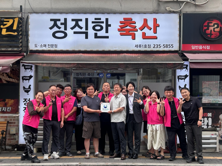 세류3동 지역사회보장협의체가 지역사회 나눔문화 확산에 기여한 정기후원업체에 '사랑나눔가게' 현판을 전달하고 기념촬영을 하고 있다.