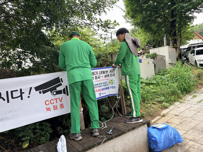 행궁동 환경관리원들이 올바른 분리배출 방법과 시간을 안내하는 현수막을 재설치하고, 느슨해진 말뚝을 보강하는 등 안내시설을 정비하고 있다.