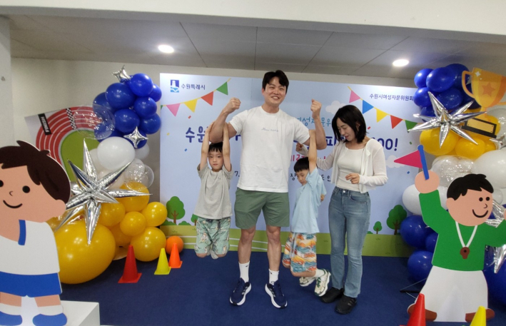 행사장 입구 포토존에서 아빠가 아이를 번쩍 들어 올리며 '수육대 피지컬 100'의 의미를 더하고 있다.