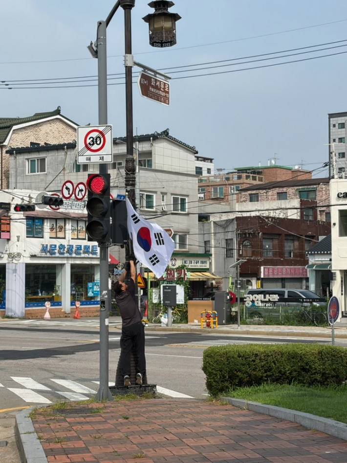 화서1동 새마을협의회 회원이 태극기를 게양하고 있다.
