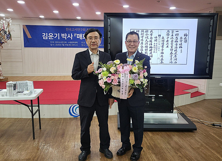 이세규 한국고서연구회 회장이 김운기 박사에게 재간을 축하하며 꽃바구니를 전달하고 있다.