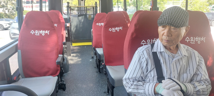 전직 교장 출신 김재섭 경로당 회장이 좌석에 앉아 있다. 좌석 맨 뒤에는 휠체어 승강기가 보인다.