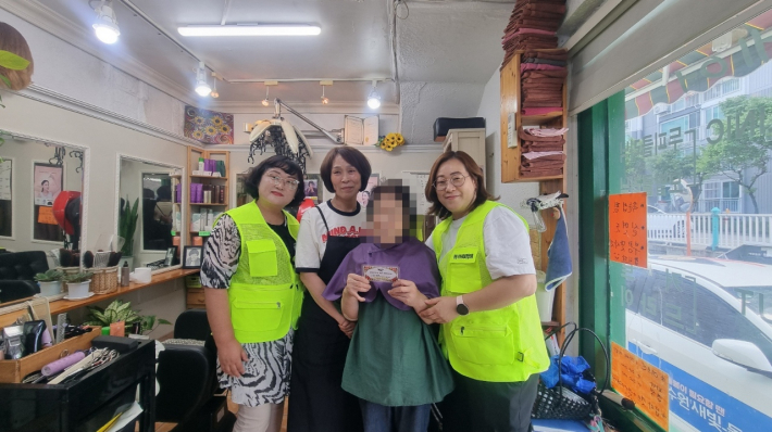 이미용서비스 이용자와 평동 지역사회보장협의체 단체원이 사진을 찍고 있다.