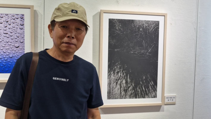남기성 작가가 안양천 박달동을 찍은 사진앞에 서 있다.