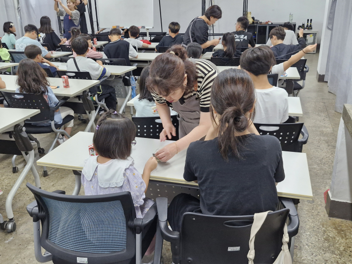 보조강사들이 아이들 사이를 돌아다니며 바느질 방법을 알려주고 있다. 