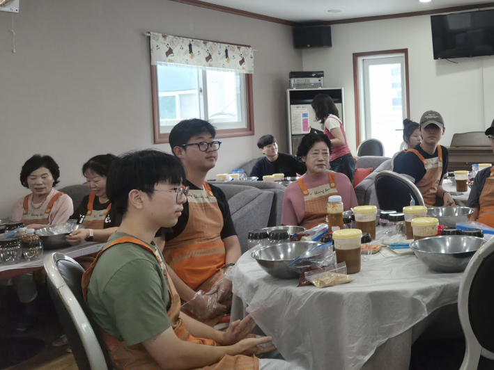 아주대 권도형 학생(왼쪽 안경쓴 학생)이 주민들과 함께 고추장 담그기 체험에 참여하며 세대 간 소통의 시간을 보내고 있다.
