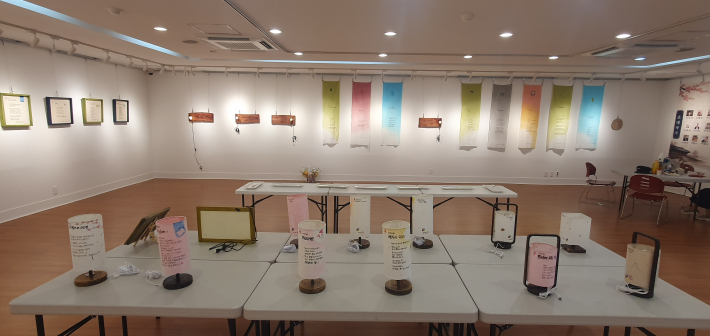 전시장 중앙의 다양한 조명 작품과 벽면의 광목 시화. 시를 생활 속 여러 재료에 옮겨 놓은 전시의 특징을 한눈에 볼 수 있다.