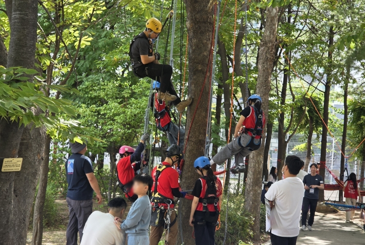 안전요원의 지도 아래 아이들이 트리클라이밍 등 모험심을 길러주는 자연 친화적 밧줄 놀이를 즐기고 있다.
