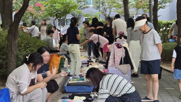 '아나바다 장터에서 주민들과 청소년들이 직접 가져온 중고 의류와 생활용품을 살펴보며 따뜻한 담소를 나누고 있다.