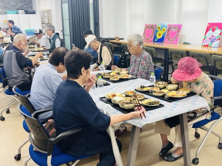 행궁동 지역사회보장협의체 위원들이 정성껏 마련한 생신상을 홀몸 어르신들께 대접하고, 어르신들이 맛있게 식사를 하며 따뜻한 정을 나누고 있다.