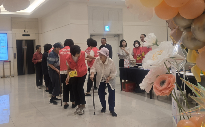 주민자치회 봉사자들이 어르신들을 반갑게 맞이하며 행사장으로 안내하고 있다.
